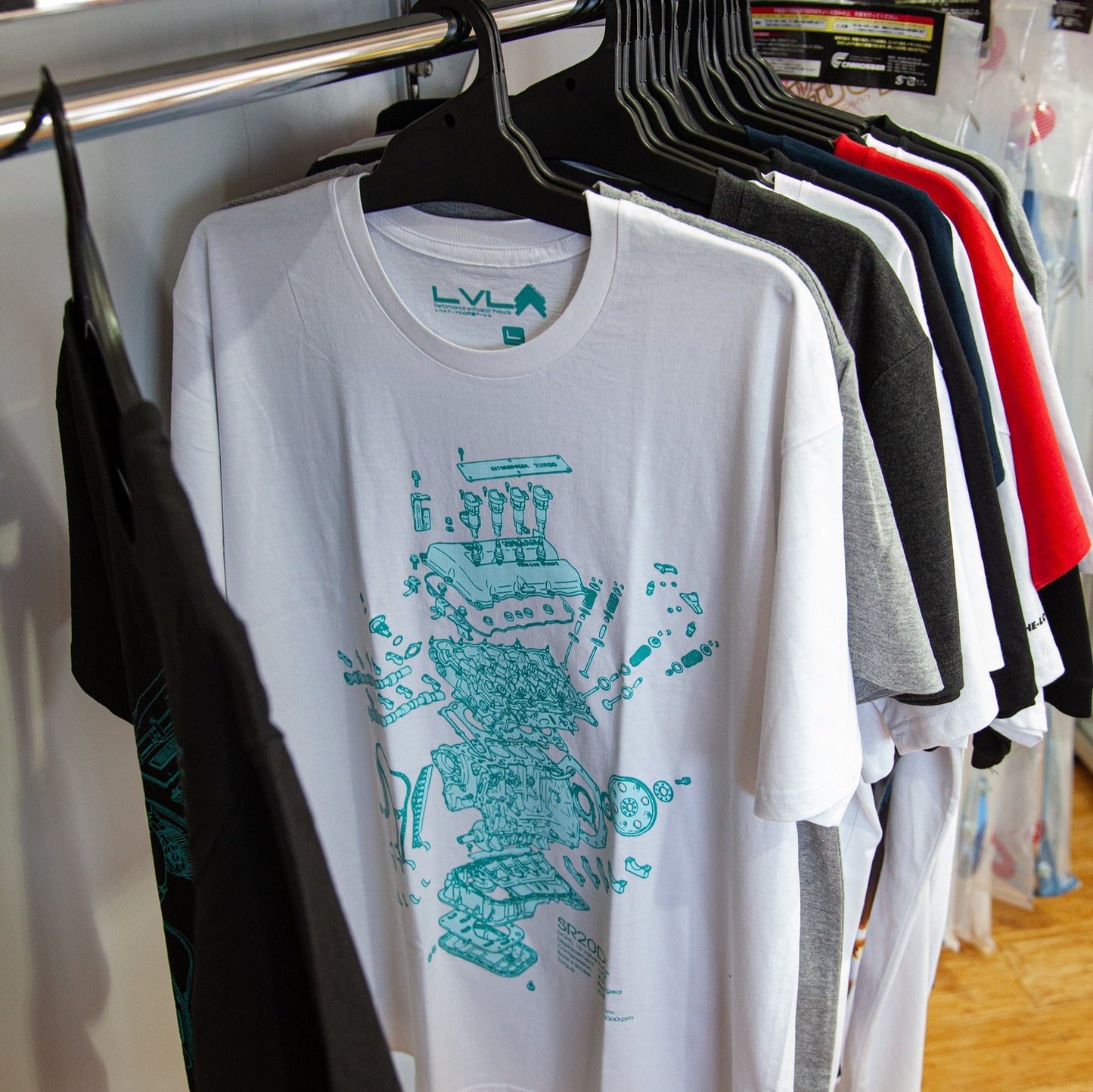 Level UP Nissan SR20 engine diagram T-shirt in white hung on a rack at a retail store